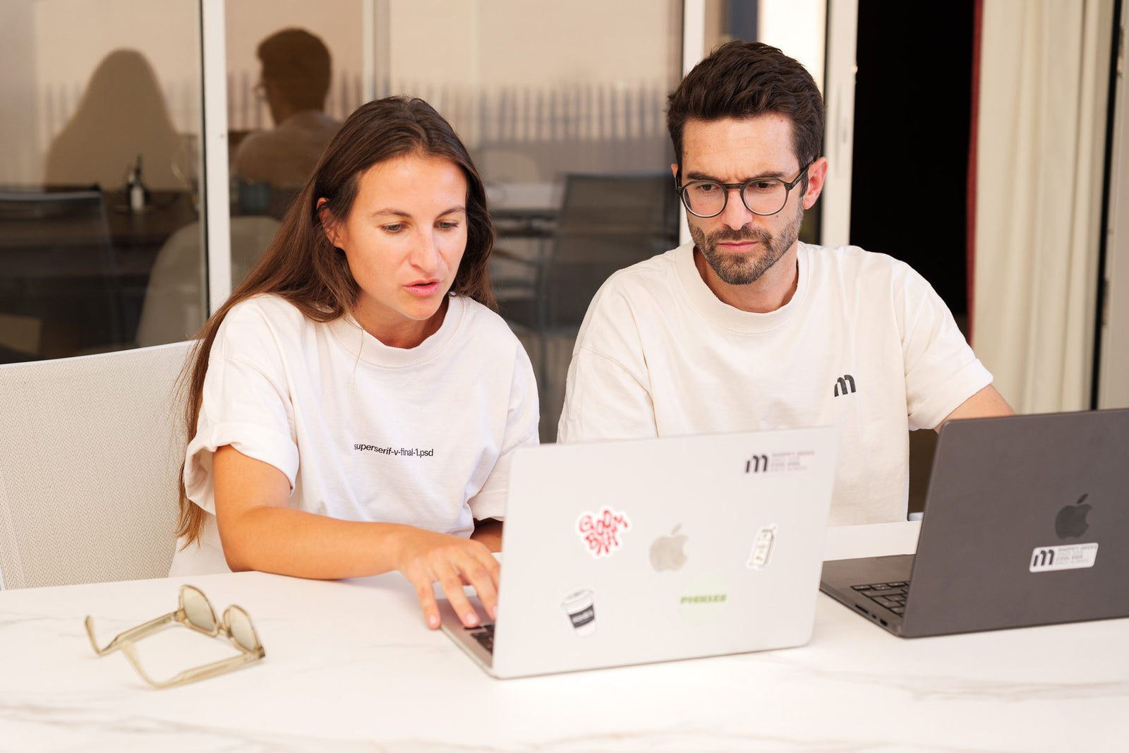 Deux membres de l'équipe Moon Moon au travail devant leurs écrans, dans les bureaux de l'agence